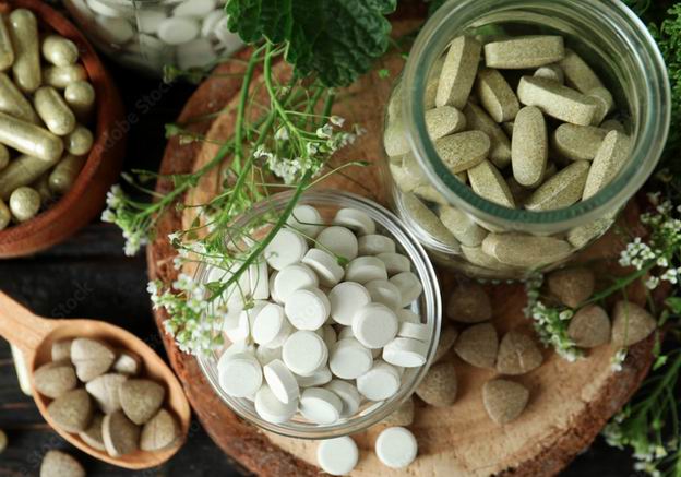 Gefäße mit weißen und grünen Tabletten und Kapseln